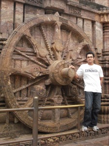 Standing besides a carved out wheel at the Sun Temple, Konark